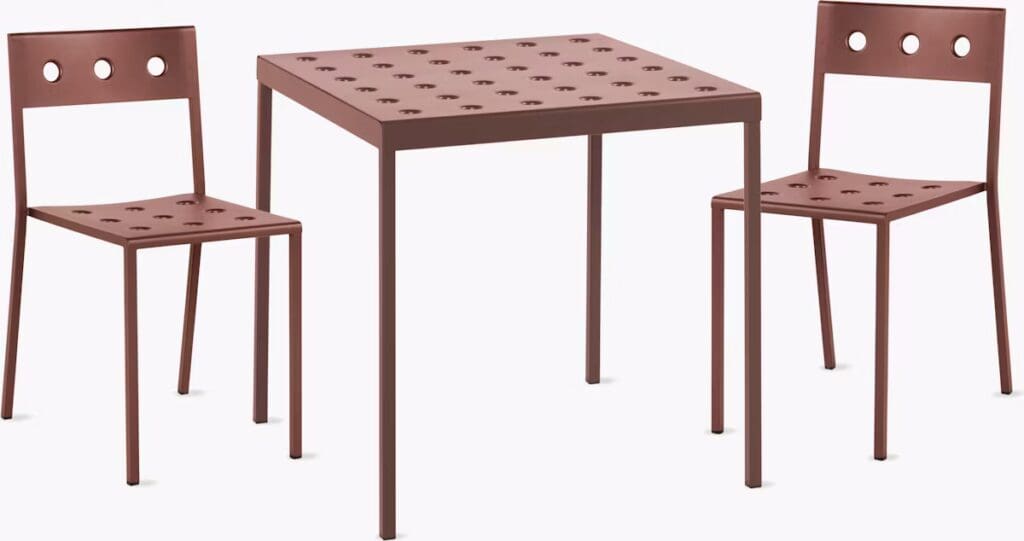 A modern table and two chairs made of brown metal featuring perforated designs, suitable for dining or casual use.