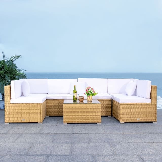 Luxurious outdoor sectional sofa with white cushions and a coffee table, set against a backdrop of a clear blue ocean.