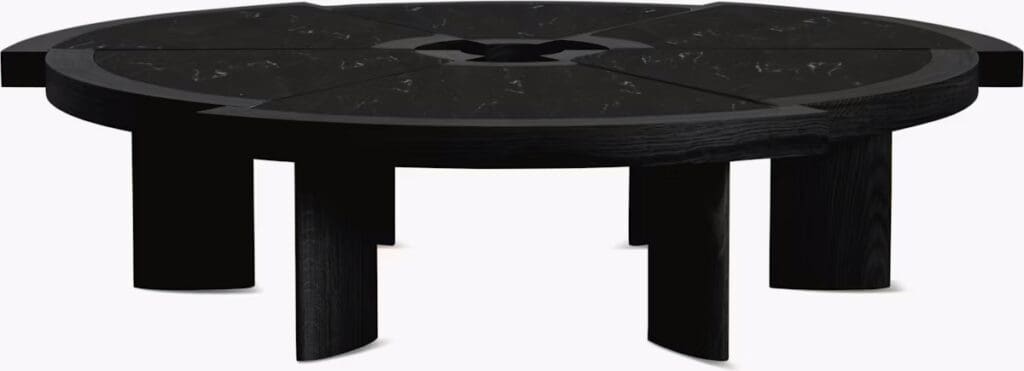 A modern round coffee table featuring a black surface with a unique segmented design and sturdy legs.