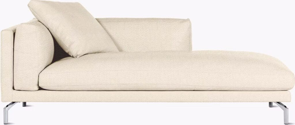 A modern cream-colored chaise lounge with a minimalist design, featuring a soft cushion and a sleek metal frame.