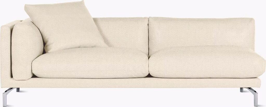 A modern beige sofa with plush cushions and a supporting metal base, featuring a decorative pillow.