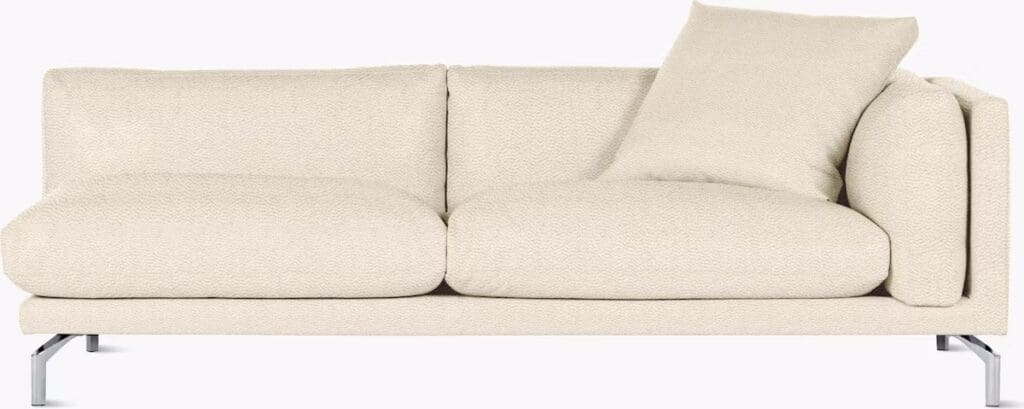 A modern beige sofa with plush cushions and a decorative pillow, featuring minimalistic design and a sleek metal base.