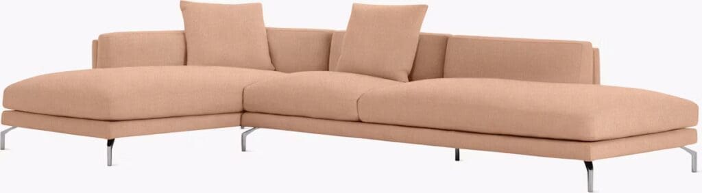 A modern beige chaise sectional sofa with plush cushions and metal legs, featuring a low backrest and decorative pillows.