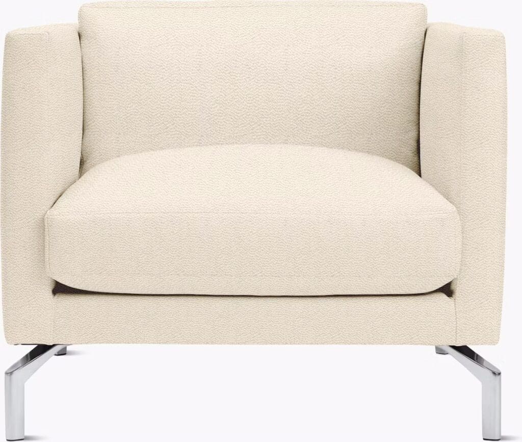 A modern cream-colored armchair with clean lines and a plush cushion, resting on sleek metal legs.