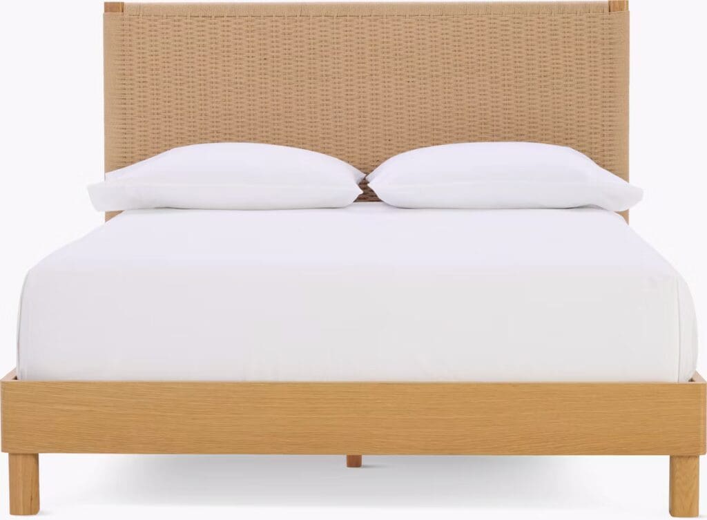 A wooden bed frame with a woven headboard and two white pillows on a white mattress.