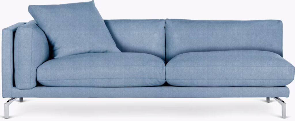 A modern blue sofa with a large back cushion and sleek metal legs, showcasing a minimalist design.
