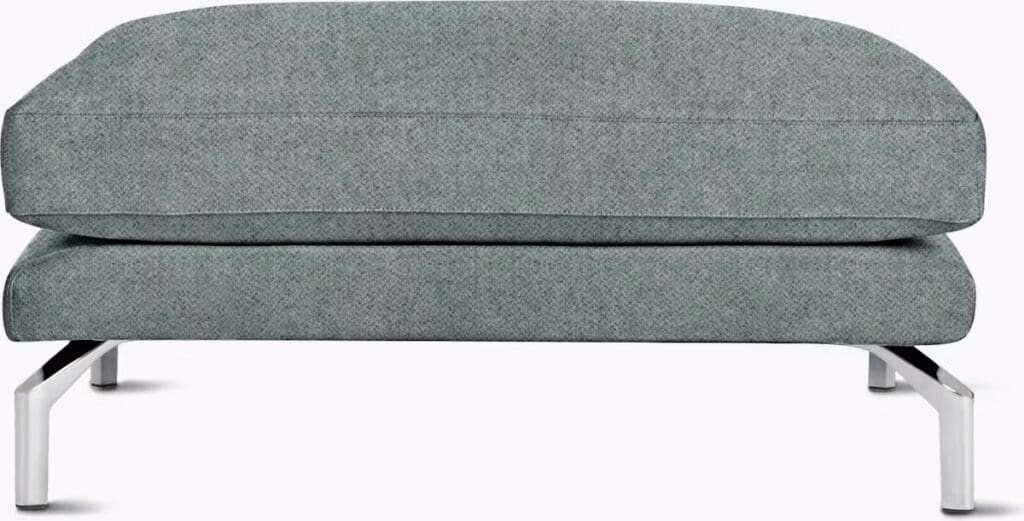 A modern sofa with a low profile, covered in a textured gray fabric, supported by sleek silver legs.