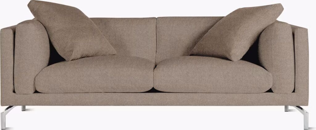 A modern brown sofa with loose pillows, showcasing a minimalist design and metal legs, suitable for living room decor.