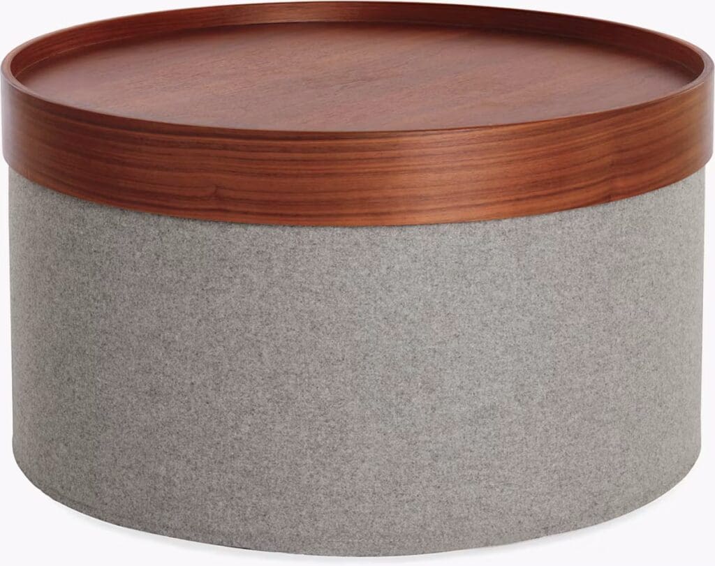 A modern, round coffee table featuring a wooden top and a grey felt base, combining style with functionality.