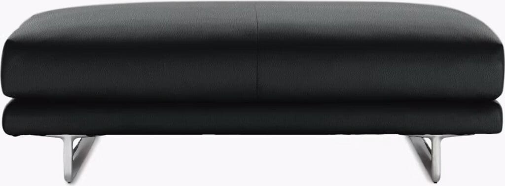 A sleek, modern black ottoman with a low profile and silver legs, designed for contemporary living spaces.