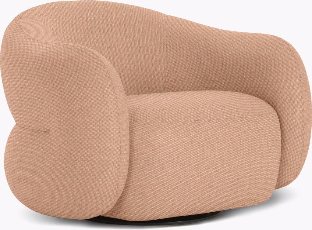 A modern, rounded armchair upholstered in soft, light pink fabric, featuring a low-profile design.