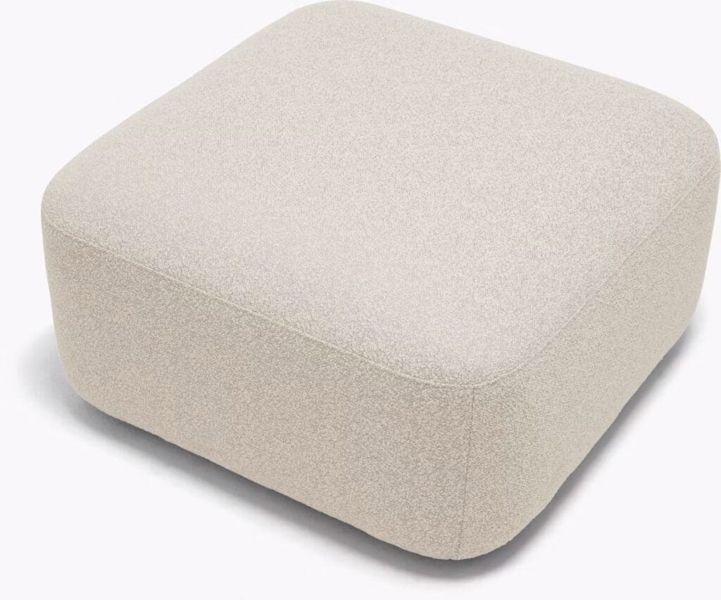 A light-colored, square pouf with rounded edges, made of textured fabric, suitable for modern living spaces.