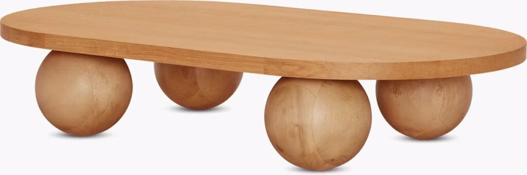 A modern coffee table with an oval wooden top supported by four spherical bases.