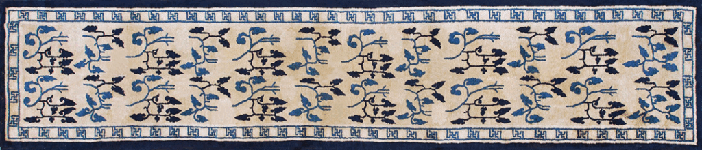 A vintage Persian rug featuring intricate floral designs in blue and black against a cream background, bordered with a geometric pattern.
