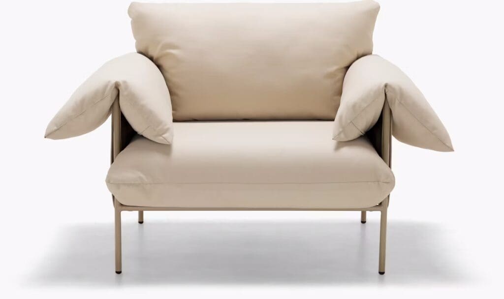 A contemporary light beige armchair featuring large, plush cushions and minimalistic metal legs, designed for comfort.