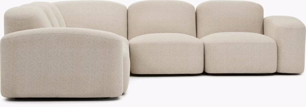 Modern, beige sectional sofa with rounded edges and cushions, designed for comfort and style.