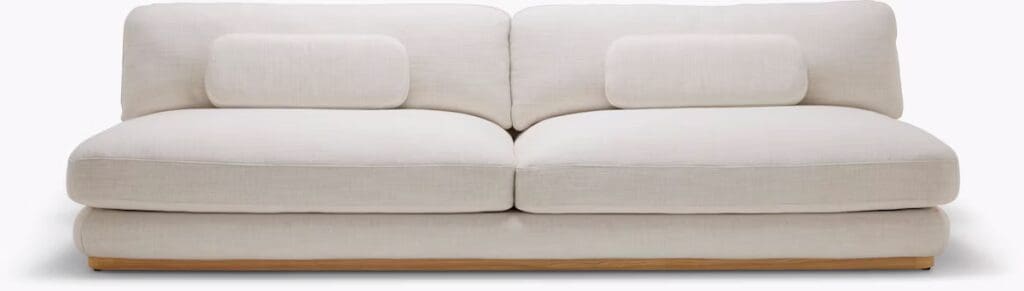 A modern, stylish white sofa with plush cushions and a wooden base, designed for comfort and contemporary aesthetics.