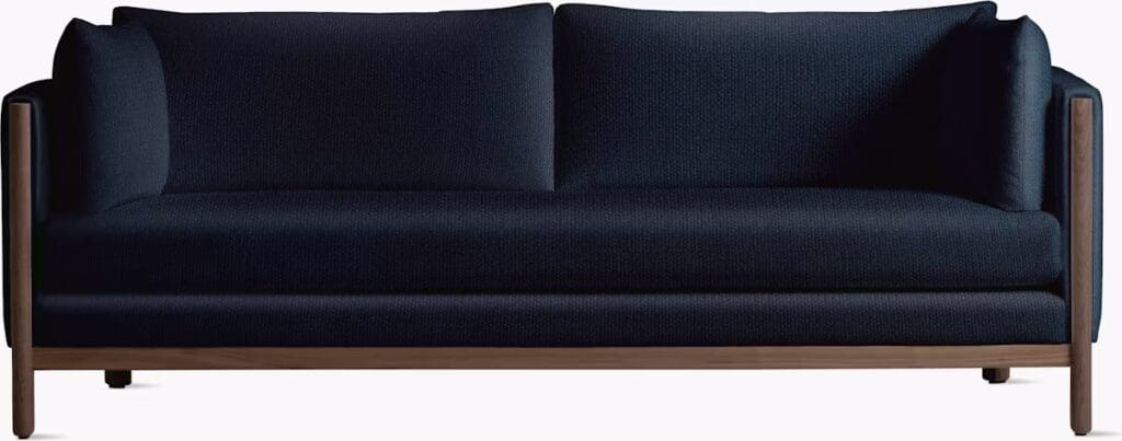 A sleek dark blue sofa with a minimalist design, featuring plush cushions and wooden accents.