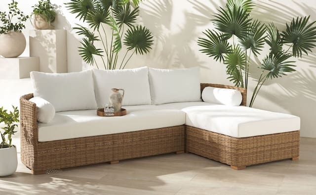 Modern outdoor sectional sofa with white cushions, surrounded by lush green plants and a minimalist aesthetic.