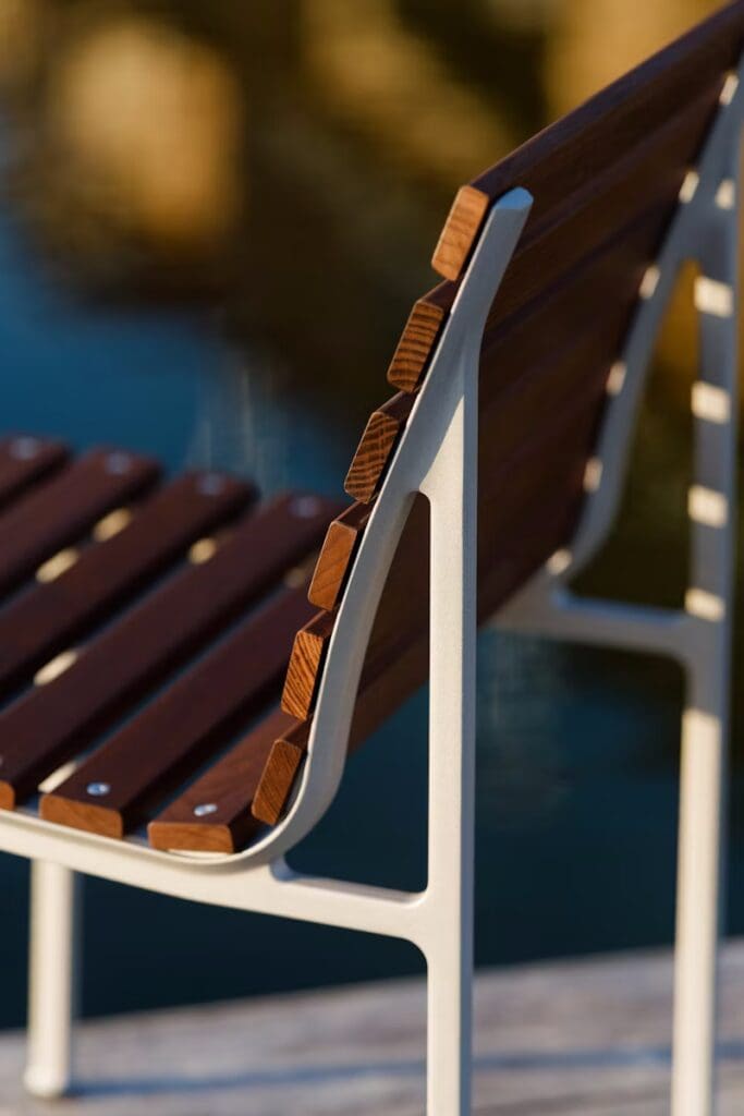 Close-up of a stylish outdoor chair featuring a wooden slatted backrest and a sleek white metal frame, suitable for modern patio decor.