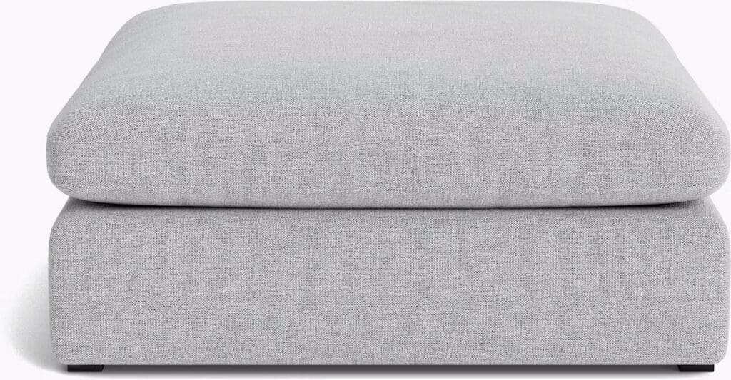 A modern gray ottoman with a plush cushion, designed for comfort and style.
