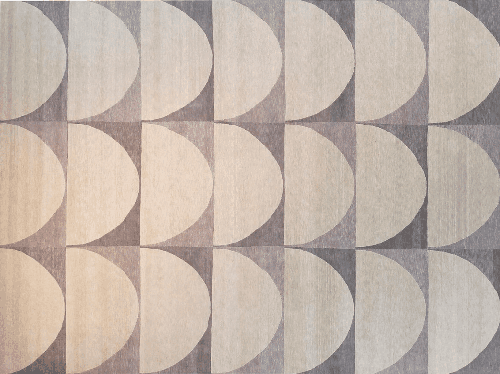 A geometric rug featuring circular and semi-circular patterns in beige and gray tones, arranged in a symmetrical design.