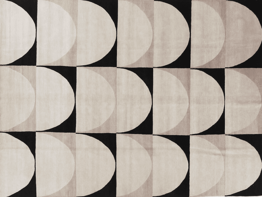 A patterned rug featuring a geometric design with alternating circles and semicircles in shades of beige, black, and light gray.