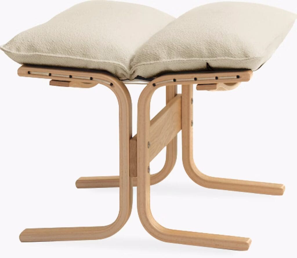 A modern wooden stool with a unique curvy design and two plush cushions on top.