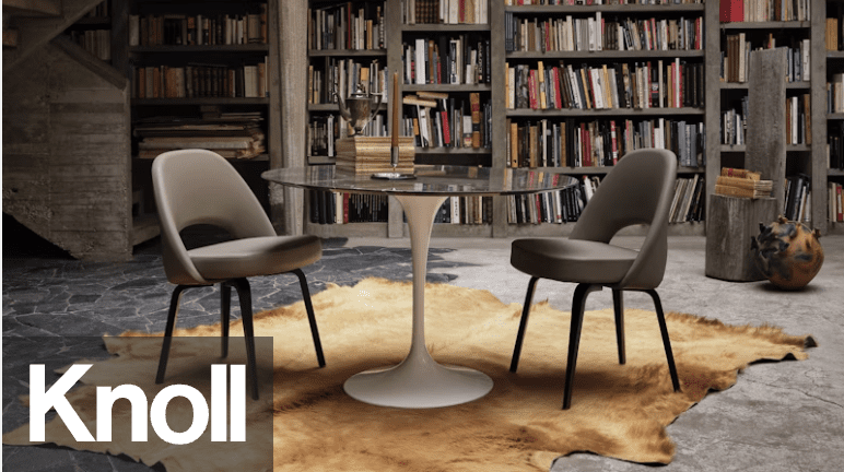A modern dining area featuring a round glass table with a white base, accompanied by two stylish gray chairs on a cowhide rug, with a backdrop of bookshelves filled with books.