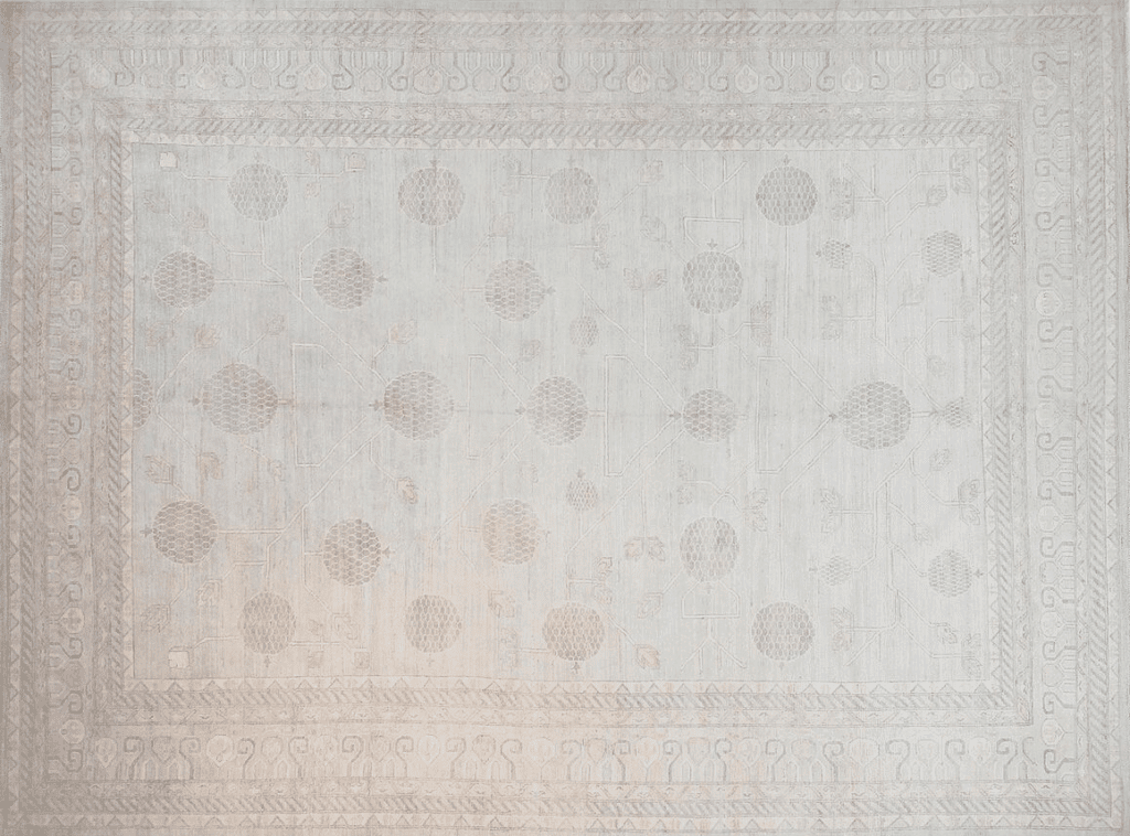 A light-colored vintage rug featuring subtle floral motifs and geometric patterns, bordered with intricate designs.