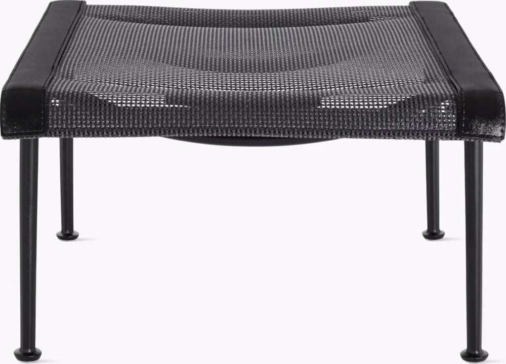 A modern and minimalistic coffee table featuring a mesh top with a sleek black finish and thin black legs.