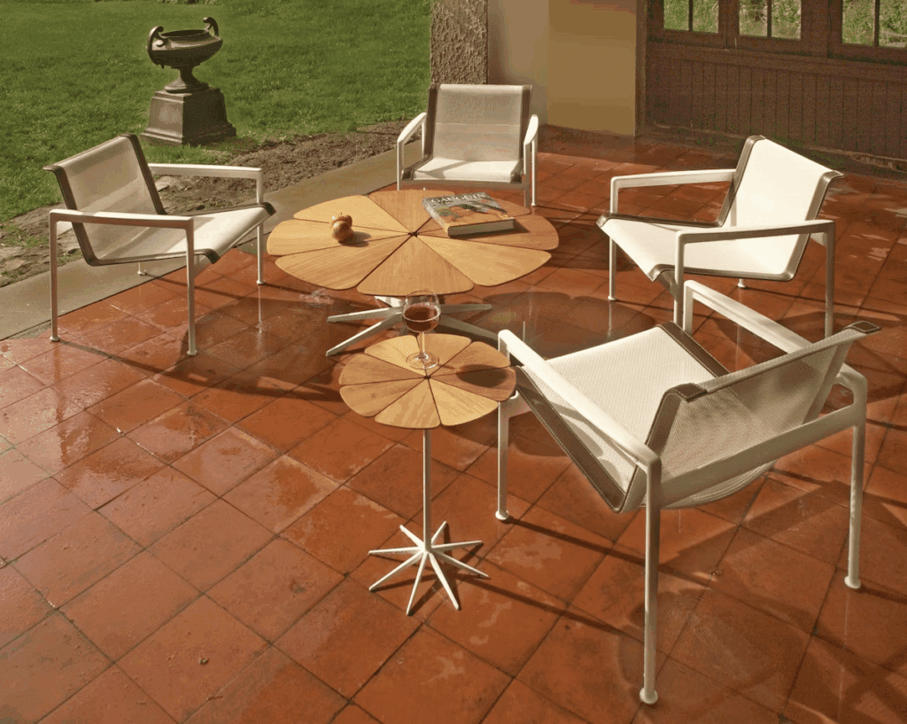 Stylish outdoor seating area featuring modern chairs and unique wooden tables on a tiled patio.