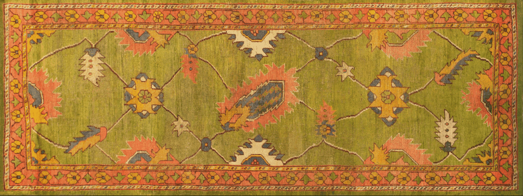 A vintage Turkish Oushak rug featuring bright floral patterns in vibrant colors like green, orange, yellow, and blue, framed by a decorative border.