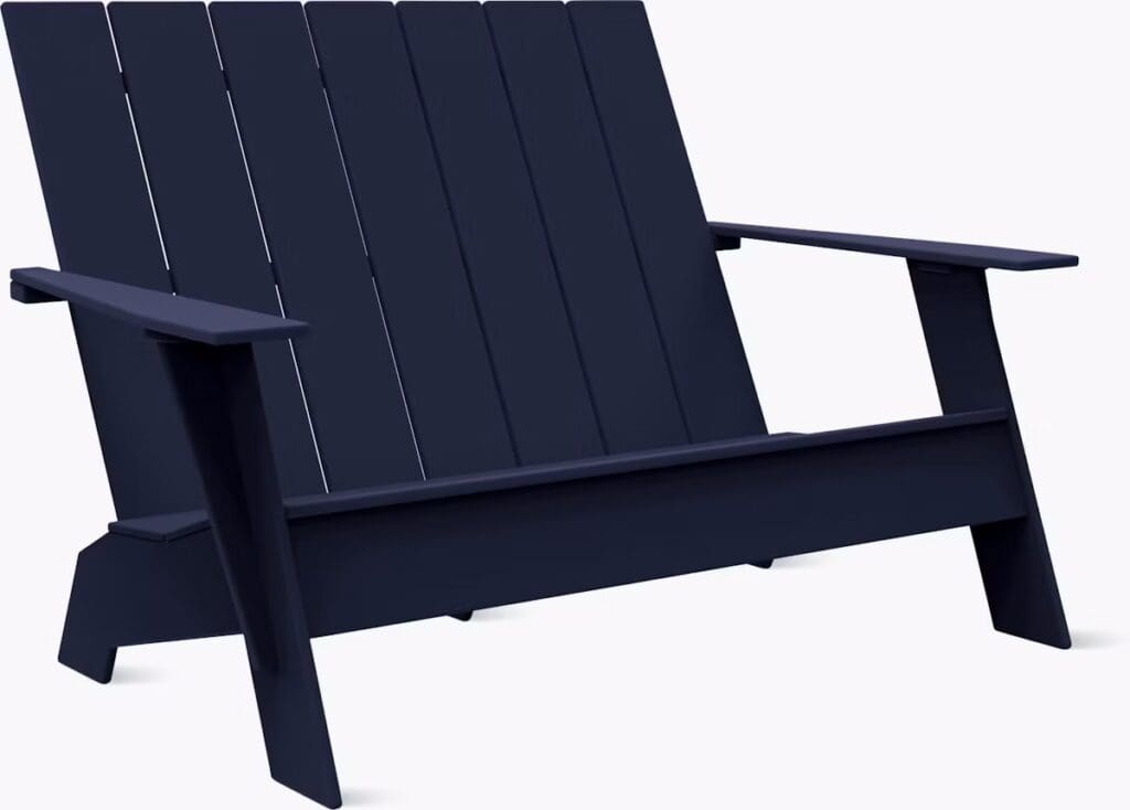 A modern navy blue Adirondack chair featuring a slatted back and wide armrests, designed for outdoor use.