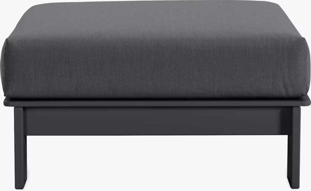 A modern ottoman with a dark gray cushioned top and a sturdy black wooden base, designed for versatility in contemporary living spaces.