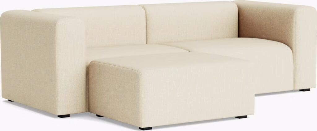A modern beige sectional sofa with rounded edges and a matching ottoman.