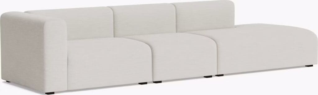 A modern sectional sofa in a light neutral fabric, featuring a contemporary design with rounded edges and a low profile.
