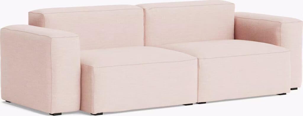 A modern, minimalist pink sectional sofa with a clean design and rounded edges, featuring spacious seating areas.