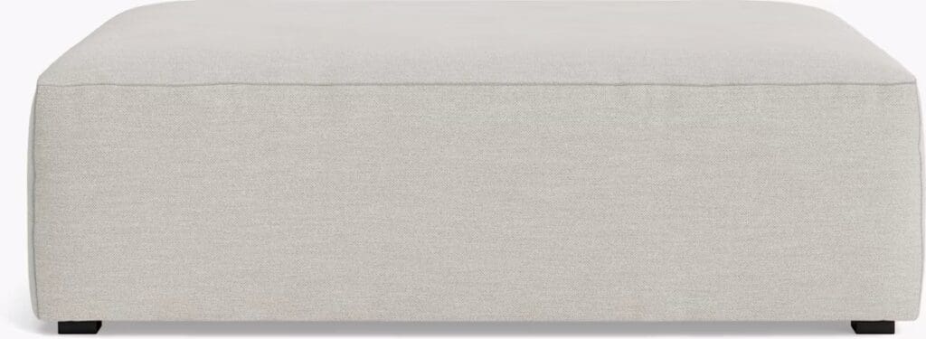 A modern cream-colored ottoman with a simple design and black legs.