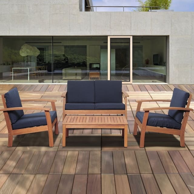 Modern outdoor living space featuring a three-piece seating arrangement with navy blue cushions, set on a wooden deck, overlooking a contemporary glass facade.