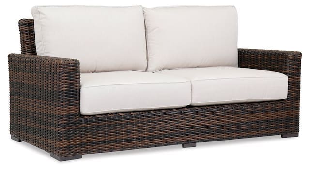 Stylish outdoor sofa with a woven wicker frame and cream-colored cushions, designed for comfortable relaxation in an elevated outdoor space.