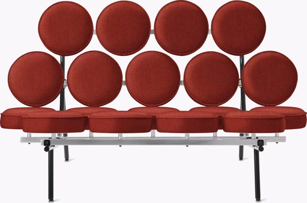 A modern red sofa featuring circular cushions arranged in a unique pattern, supported by a sleek metal frame.
