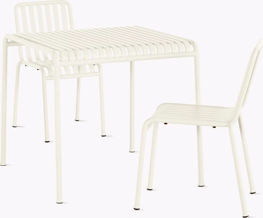 A minimalist white metal dining table with matching chairs featuring slatted designs.