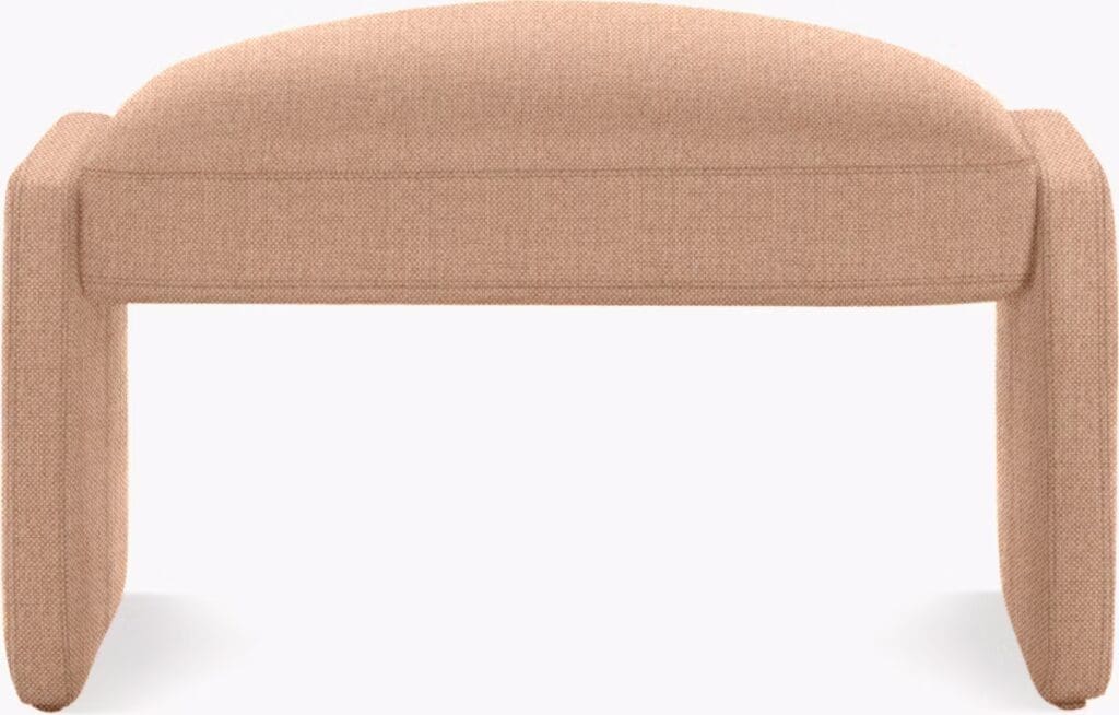 A modern, soft, upholstered bench with rounded edges and sturdy legs, featuring a warm beige color, suitable for contemporary living spaces.