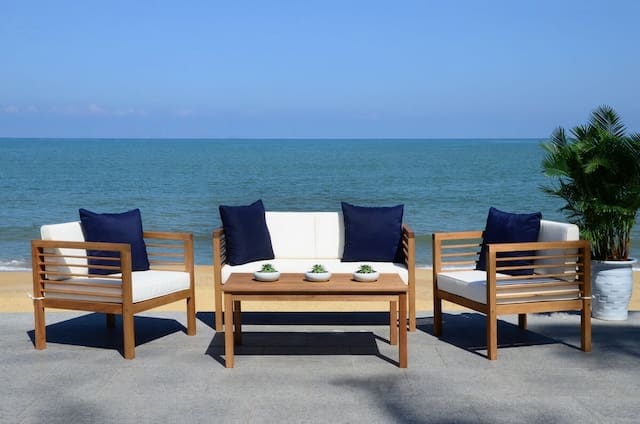 Stylish outdoor seating area with wooden furniture and navy blue cushions, overlooking a serene ocean view.