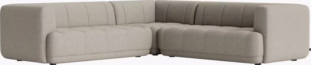 A modern light gray sectional sofa with tufted upholstery and a low profile design, featuring clean lines and a contemporary aesthetic.