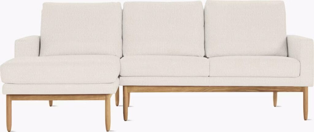 A modern light-colored sectional sofa with wooden legs, featuring a chaise on one side and plush cushions for comfort.
