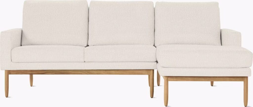 A modern beige sectional sofa with wooden legs and a chaise lounge on one side, designed for comfort and style.