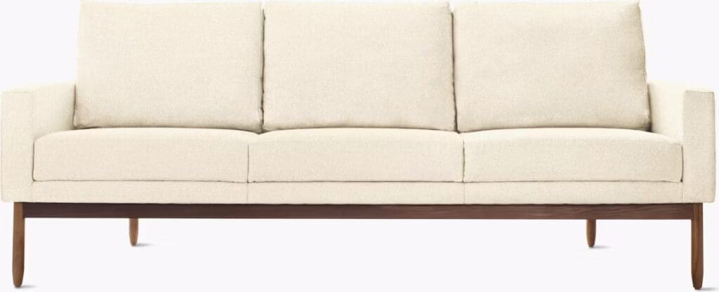 A modern, cream-colored sofa with a wooden base and three cushioned seats, designed for contemporary living spaces.