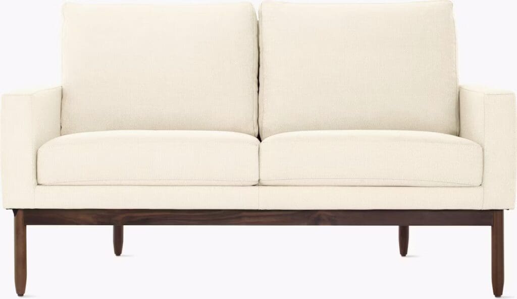 A modern cream-colored sofa with a sleek design, featuring a wooden frame and tapered legs.